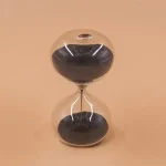Färgglad sandklocka i glas med svart och transparent sand, elegant och modern design, perfekt för vetenskaplig dekoration eller som samlarobjekt.