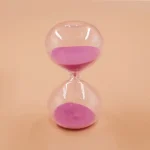Genomskinlig glasstopp med rosa sand, symboliserar tid och tålamod, idealisk för vetenskaplig eller pedagogisk dekoration.