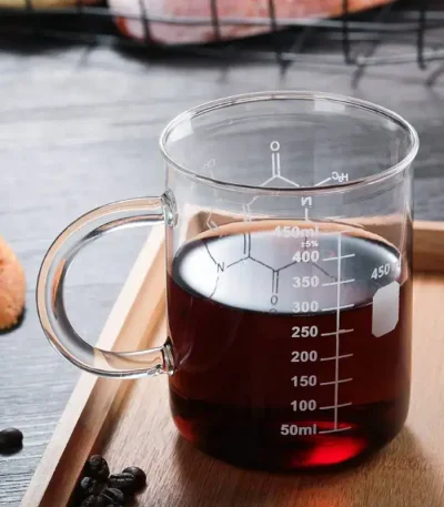Laboratoriekopp i glas som innehåller en mörk vätska, graderad för att mäta volymen exakt, idealisk för vetenskapliga experiment eller temadekor.