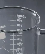Transparent bägare i glas med millilitermarkeringar, används i laboratoriet för att mäta vätskor med precision.