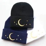 Ullmössa med mån- och gyllene stjärnmotiv, finns i svart, mörkblått och vitt. Perfekt för en mysig och trendig stil, idealisk för vintern eller som en originalaccessoar.