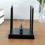 Klassisk Newtonpendel med hängande metallkulor, idealisk för vetenskaplig dekoration eller som utbildningsobjekt i ett kontor eller klassrum.