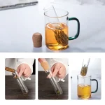 Te-mugg i glas med infuser, innehållande bryggt te, på vit bakgrund.