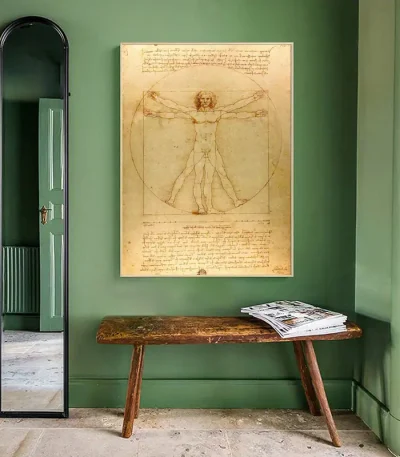 Reproduktion av den berömda teckningen av Leonardo da Vinci, som visar Vitruviusmannen med sina ideala proportioner, upphängd på en grön vägg i ett elegant rum.