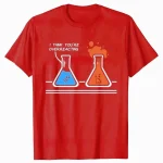 T-shirt med illustration av två laboratoriefällor, en blå och en orange, med en humoristisk fras "Je pense que tu en fais trop" högst upp.