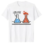 Vit t-shirt med illustration av två laboratoriefällor, en blå och en röd, som uttrycker en humoristisk kemisk reaktion med texten "I think you're overreacting".