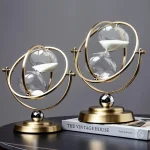 Dekorativ klocka i form av timglas med glasbollar och struktur i gyllene metall, inspirerad av astronomisk stil, idealisk för inredning.