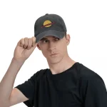 Ung man som bär en svart keps med planetlogo, tittar åt höger, vit bakgrund.
