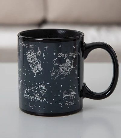Svart keramikmugg med illustrationer av stjärntecken: Tvillingarna, Skytten, Lejonet, Väduren och fler, med namn på franska.