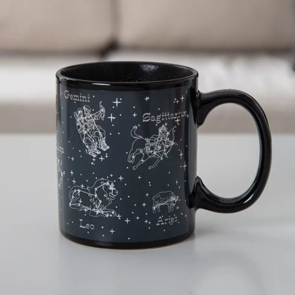 Svart keramikmugg med illustrationer av stjärntecken: Tvillingarna, Skytten, Lejonet, Väduren och fler, med namn på franska.