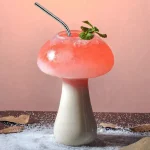 Svampformad glas med en rosa cocktail och en mynta kvist, dekorativ och originell.