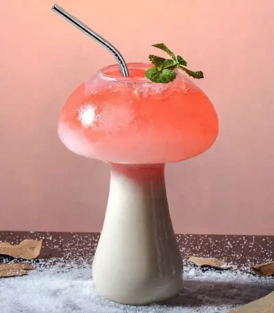 Svampformad glas med en rosa cocktail och en mynta kvist, dekorativ och originell.
