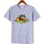 Grå t-shirt med design av Rubik's kub i nedbrytning, som illustrerar en rörelse- och dekonstrueringseffekt av det berömda pusslet.