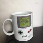 Mugg i form av en Game Boy-konsol med skärm som visar "Super Mario Land" och färgglada knappar, idealisk för retro videospelsfans.