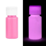 Flaska med fluorescein i rosa och lila, som illustrerar luminescens under UV-ljus, använd i vetenskap för detektion och observation.