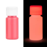 Flaska med rosa fosforescerande färg synlig i normalt ljus och under UV-ljus, som illustrerar skillnaden i utseende i mörkret.
