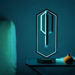Modern LED-lampa i form av en nyckel, belyst med blått ljus, placerad på ett bord med en liten vas och en bok, dekorativ och innovativ för en vetenskaplig eller teknologisk inredning.