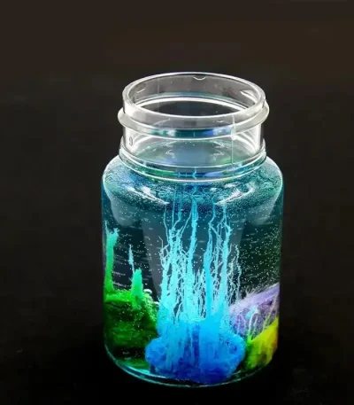 Glasvas som innehåller ett vetenskapligt experiment med färgade vätskor och bubblor, som illustrerar ett fängslande kemiskt eller fysikaliskt fenomen.