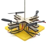 Pedagogisk drönare med propellrar, trästruktur och bas i gul skum, utformad för att lära sig om robotik och mekanik. Perfekt för vetenskapliga och pedagogiska projekt.