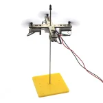 Vetenskaplig experimentbänk med trästöd, elektroniska komponenter och filament för utbildningsexperiment inom fysik och vetenskap.
