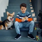 Ung pojke med en hund som leker med en Rubik's kub på en trappa, avslappnad och lekfull atmosfär.
