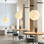 Lysande hängande lampa i form av en måne, modern inredning med tre runda hängande lampor, varm atmosfär och ren design i ett samtida utrymme.
