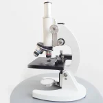 Vitt vetenskapligt mikroskop för noggrann observation i laboratorium eller hemma. Idealisk för studier av små objekt, celler eller mikroorganismer med hög upplösning.