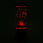 Luminös röd lavaflaska i mörkret, med synliga gasbubblor inuti, som skapar en fängslande visuell effekt.