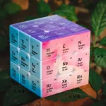 Dekorativ kub som representerar det periodiska systemet av kemiska element, med klara färger och detaljerade symboler och atomnummer.