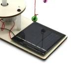Solpanel som illustrerar en utbildningsupplevelse med ett vetenskapligt objekt, inklusive en solanordning, en röd tråd och en hängande kula, perfekt för att lära sig om solenergi.