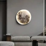 Väggdekoration som föreställer månen i relief, belyst, i ett modernt hem med grå soffa och soffbord.