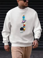 Sweatshirt med illustration av en rymdutforskare som tittar på en torn av balanserade planeter.