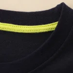 Svart t-shirt med reflexband i gult, idealisk för säkerhet och sport, tillverkad av högkvalitativ bomull för optimal komfort.