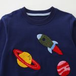 Barntröja med broderat motiv av raket och planeter.