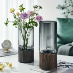 Transparent glasvas med träbas, idealisk för inredning och presentation av färska eller konstgjorda blommor.