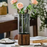 Rosa blommor i en glasvas med träbas, elegant och modern dekoration för inomhus.