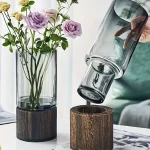 Glasvas med blommor och trästöd, modern och naturlig dekoration, perfekt för att försköna ditt hem med en elegant och organisk touch.