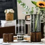 Glasvas med träbas, idealisk för färska eller konstgjorda blommor, som ger en naturlig och elegant touch till din dekoration.