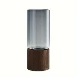 Transparent glasvas med mörk träbas, modern och elegant dekoration för hemmet eller kontoret.