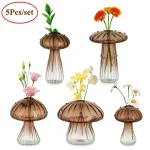 Transparenta glasvaser med svampformade lock, innehållande färgglada konstgjorda blommor, perfekta för hem- eller kontorsdekoration.