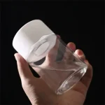 Transparent cocktailglas med vitt silikonlock, hålls av en hand, på svart bakgrund.