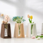 Mörk trävas, vit keramik och beige keramik, var och en innehållande färgglada konstgjorda blommor, perfekta för elegant inredning.