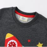 Mörkgrå t-shirt med motiv av färgglad raket, stjärnor och vetenskapliga element, perfekt för vetenskaps- och astronomientusiaster.