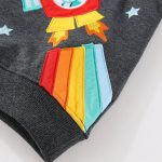 Barnkläder med färgglad vetenskaplig patch, raketmotiv och stjärnor, i mörkgrått tyg, perfekt för en lekfull och pedagogisk dekoration.