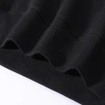 Detalj av en tryckning "Never Trust an Atom" på ett svart plagg, som framhäver det vetenskapliga budskapet med en modern och stilren design.