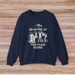 Mörkblå sweatshirt med vetenskaplig design, illustration av kvinna och djur, humoristisk text "Beam me up, this place sucks" för vetenskaps- och stilmedvetna.