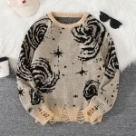 Beige ulltröja med svarta galax- och stjärnmönster, perfekt för en mysig och original look.
