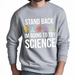 Grå sweatshirt med humoristiskt budskap om vetenskap, "Håll dig tillbaka, jag ska försöka med vetenskap", med färgglada labbikoner.